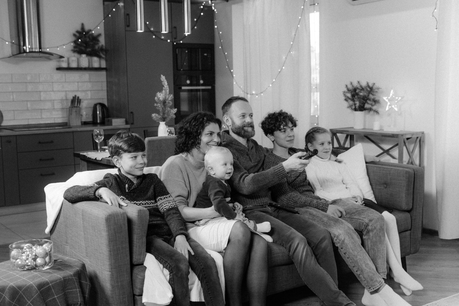 A happy family of six enjoying a cozy time together at home in a monochrome setting.